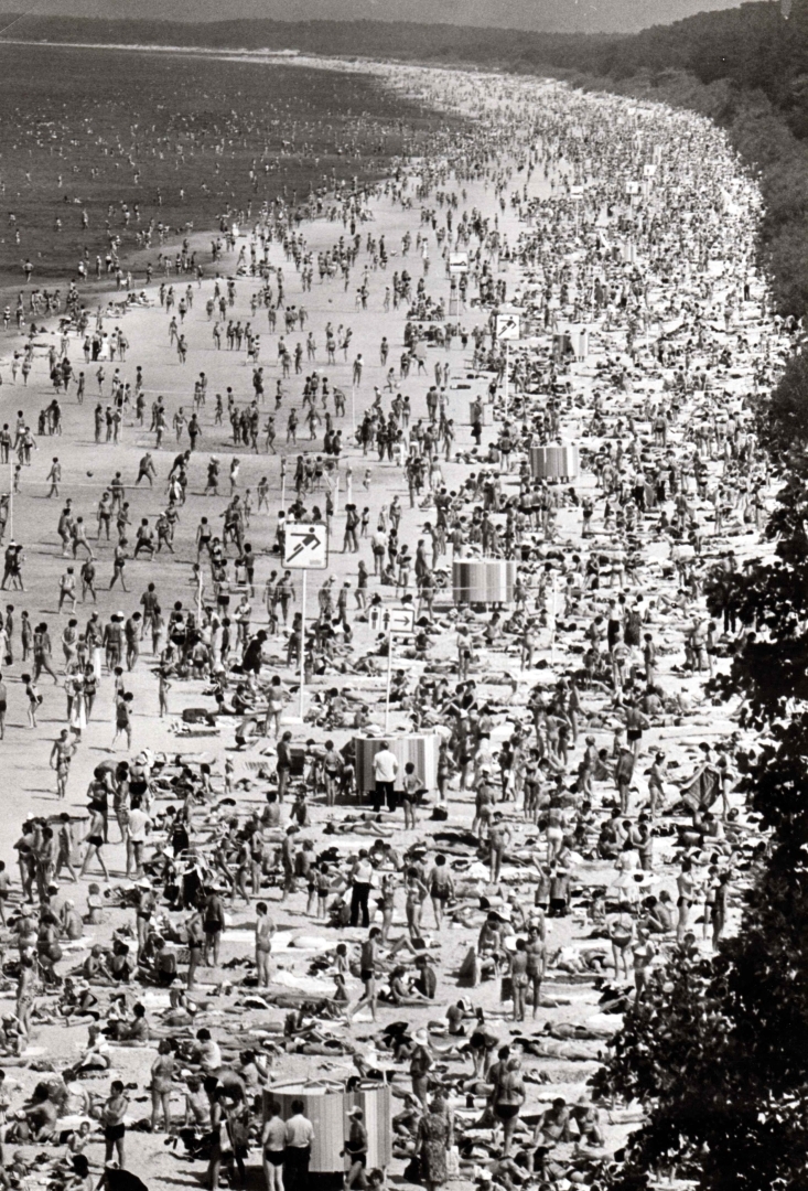 Melnbalta fotogrāfija. Vasara, skats no augšas - cilvēkiem pārpildīta pludmale.