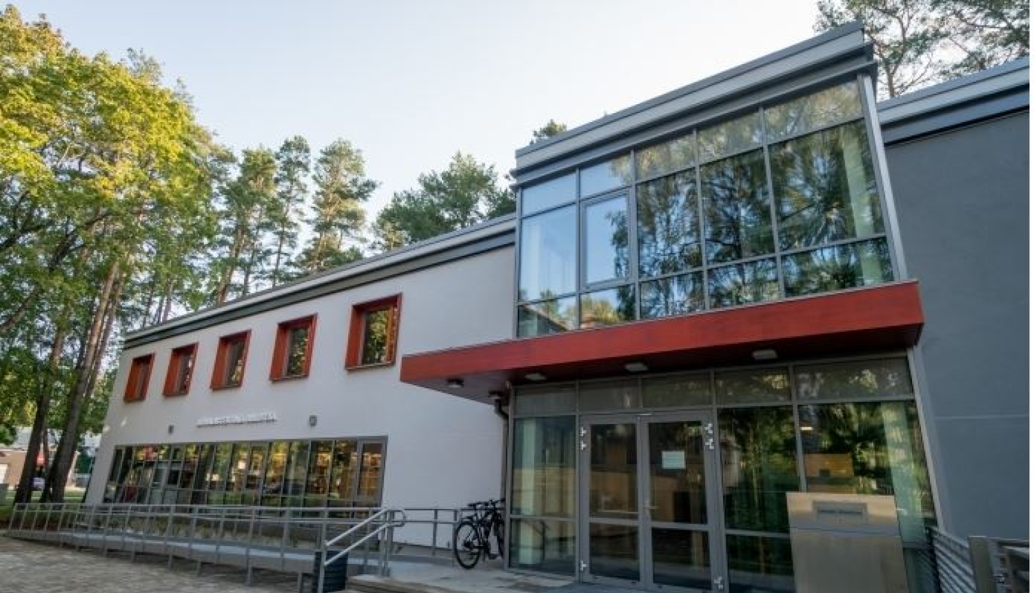 Bibliotēkas ēka, gaiša fasāde ar sarkaniem elementiem