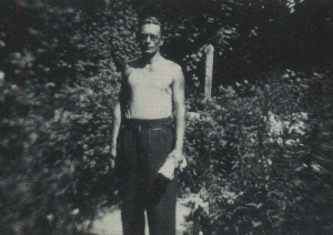 Melnbalta fotogrāfija. Vasaras skats. Trīs sievietes sēž dārzā uz sola, aiz viņām stāv divi vīrieši. 